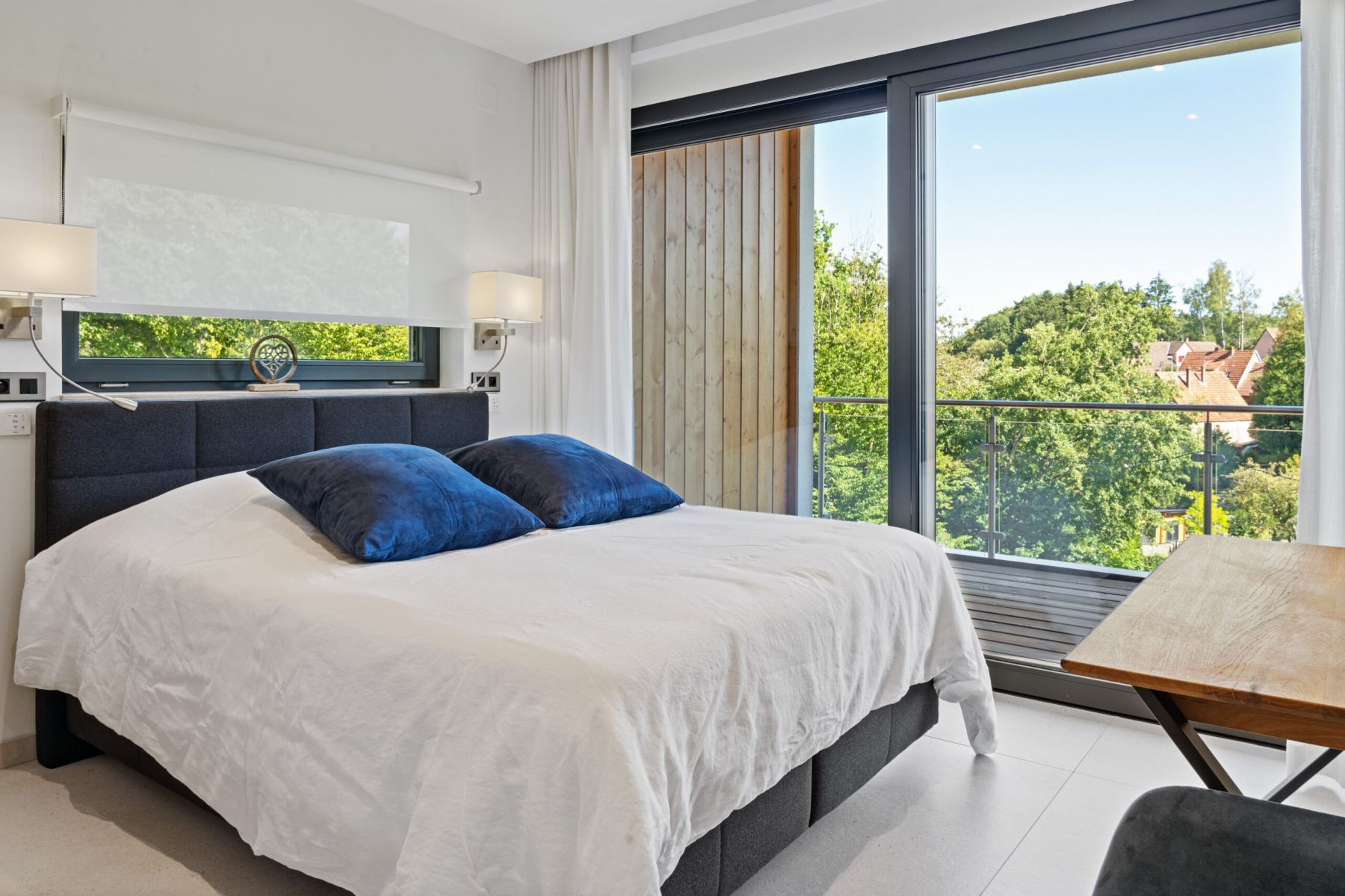 Photographe immobilier à Haguenau – chambre moderne avec lit double et vue balcon lumineux