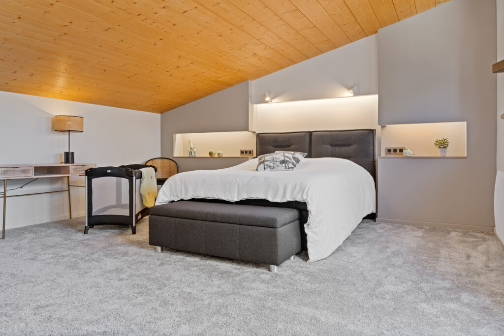 Photographe immobilier à Haguenau – chambre moderne avec lit double et plafond bois